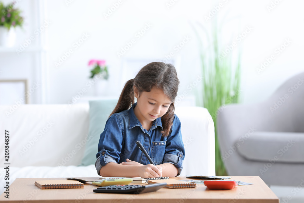 Little girl counting money at table indoors Little girl counting money at table indoors