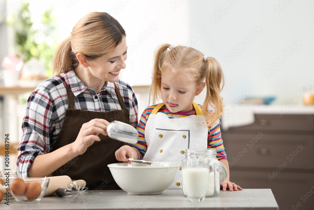 Mother with daughter making dough together in kitchen Mother with daughter making dough together in kitchen