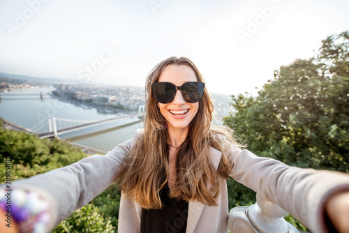 Young pretty woman making selfie photo on the beautiful cityscape background in Budapest city, Hungary