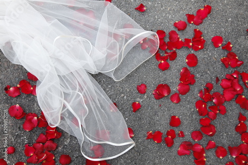 dettaglio di un velo da sposa su petali rossi per terra photo