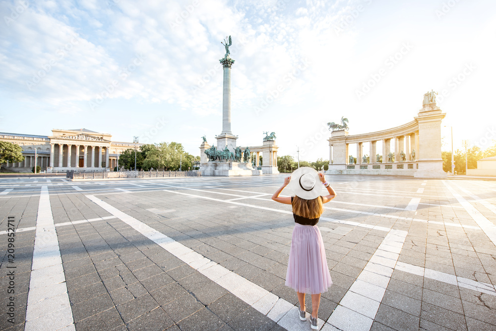Fototapeta premium Plac bohaterów z młodą turystką stojącą z powrotem w świetle rana w mieście Budapeszt, Węgry