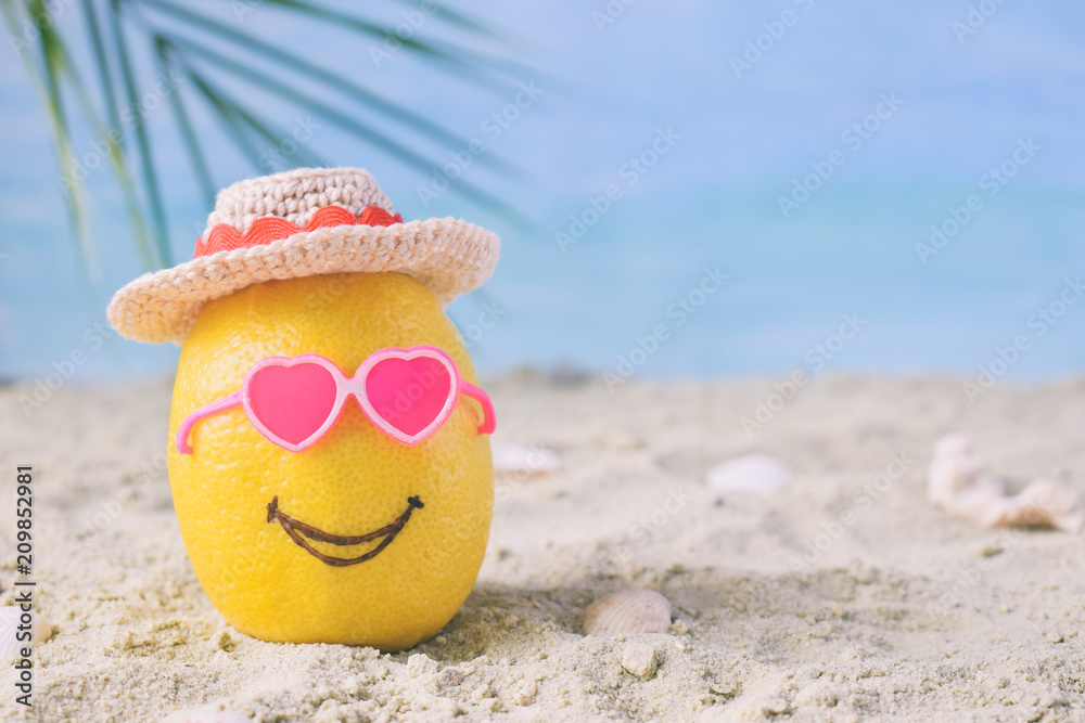 Creative minimal summer idea. Lemon citrus hipster in pink sunglasses and bamboo hat on sand. Tropical beach concept. Creative art. Fun party Mood. Copy space
