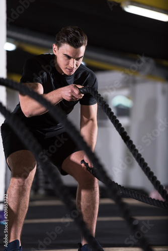 athlete man doing battle ropes cross fitness exercise