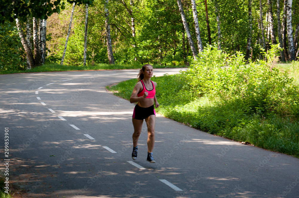 Beautiful smiling woman running in the park in the morning. Fitness girl running in the park. Running woman. Female Runner Jogging during Outdoor Workout in a Park. Beautiful fit Girl. Beautiful smiling woman running in the park in the morning. Fitness girl running in the park. Running woman. Female Runner Jogging during Outdoor Workout in a Park. Beautiful fit Girl.
