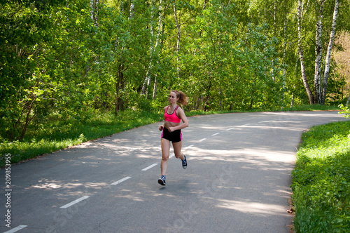 Beautiful smiling woman running in the park in the morning. Fitness girl running in the park. Running woman. Female Runner Jogging during Outdoor Workout in a Park. Beautiful fit Girl.