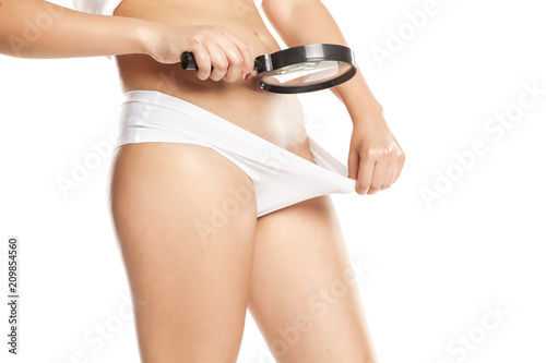 woman looks at her vagina with a magnifying glass on white background