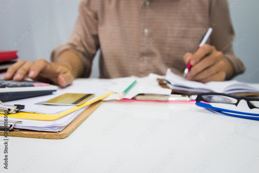 custom made wallpaper toronto digitalbusinessman using calculator and holding pen on tax paper in office.Accounting.concept.