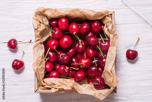 Lot of cherry in kraft cardboard box on wooden table