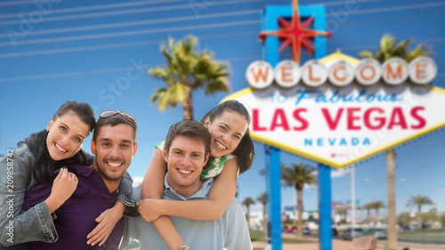 tourism, travel and summer holidays concept - group of happy friends over welcome to fabulous las vegas sign background © Syda Productions