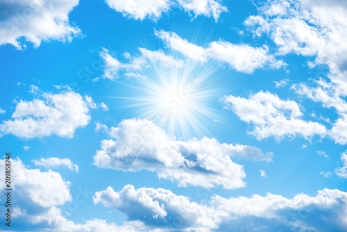 Sun with sun rays and clouds on blue sky as nature background