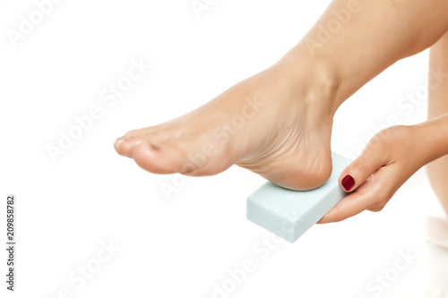 woman file her feet with a pumice stone on white background
