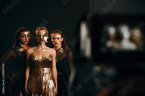 Fotografie Blurred camera in the foreground and three girls in the background