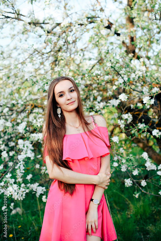beautiful young girl in pink dress in spring blossoming apple