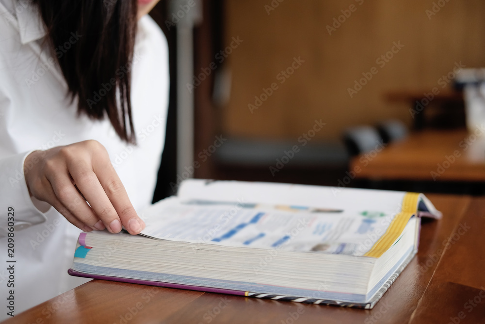 Closeup asian woman reading text book in library.