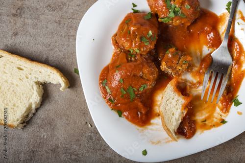 Meatballs with tomato sauce and fresh chopped parsley on plate with bread photo