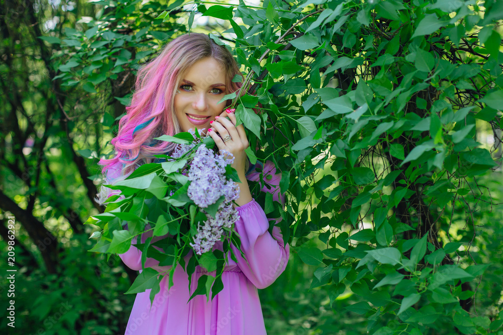 Beautiful girl with colorful dyed hair and perfect makeup and hairstyle standig next to lilac bush Beautiful girl with colorful dyed hair and perfect makeup and hairstyle standig next to lilac bush