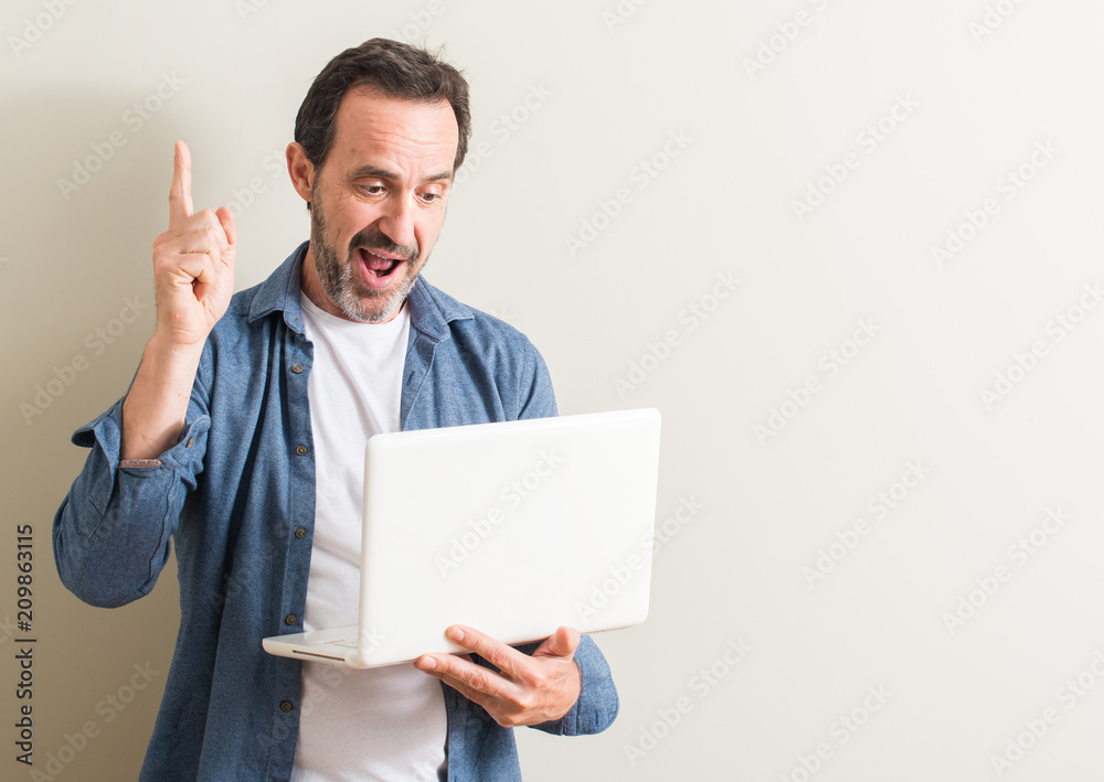 Senior man using laptop computer surprised with an idea or question pointing finger with happy face, number one Senior man using laptop computer surprised with an idea or question pointing finger with happy face, number one