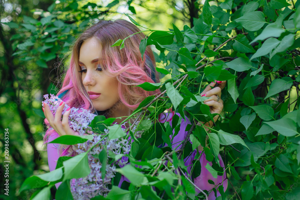 Beautiful girl with colorful dyed hair and perfect makeup and hairstyle standig next to lilac bush Beautiful girl with colorful dyed hair and perfect makeup and hairstyle standig next to lilac bush