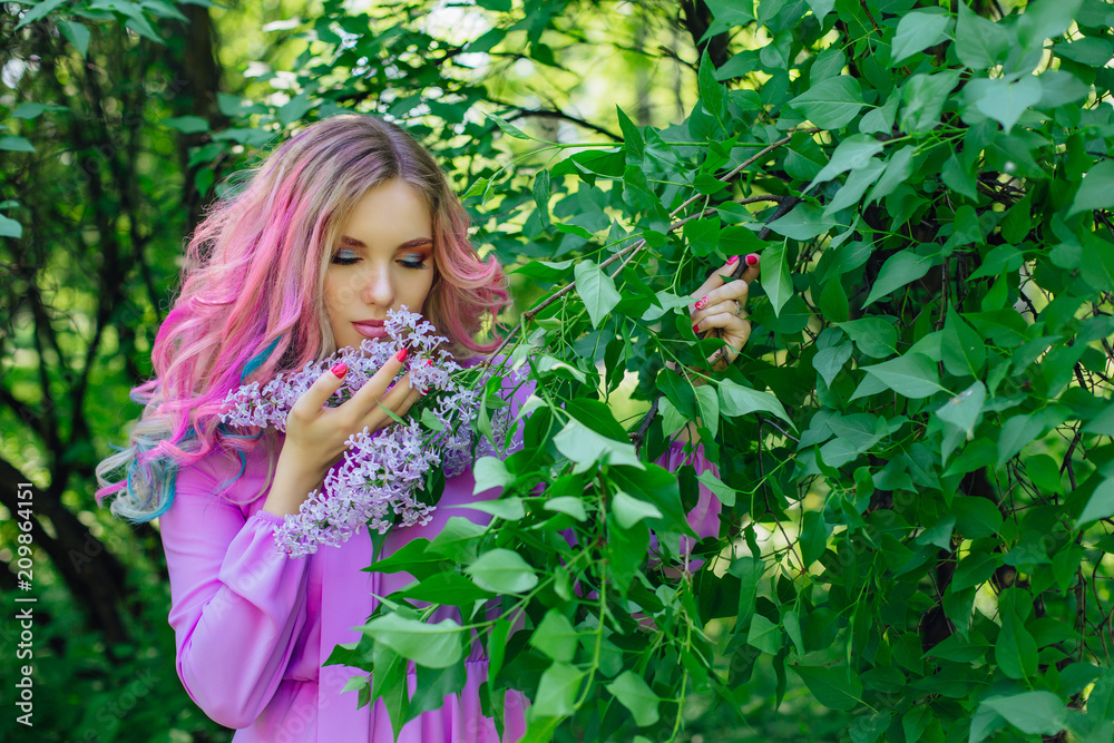 Beautiful girl with colorful dyed hair and perfect makeup and hairstyle standig next to lilac bush Beautiful girl with colorful dyed hair and perfect makeup and hairstyle standig next to lilac bush