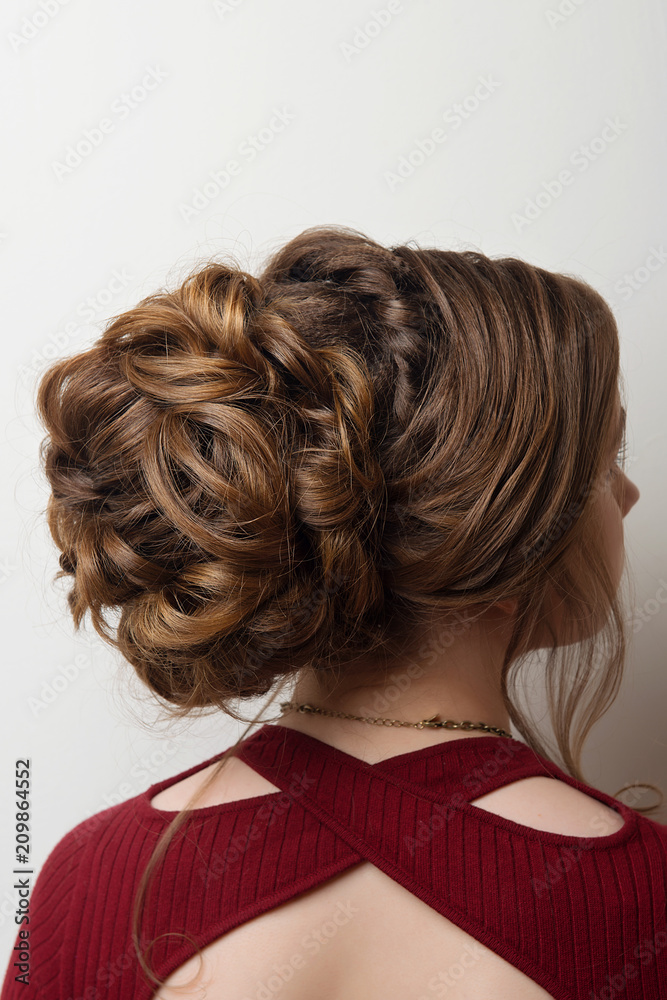 Obraz premium Wedding hairstyle bun on the head of brown-haired women on a gray background close-up rear vie