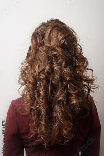 Women's hairstyle Eastern tail on the head of the girl brown-haired back view close-up on a gray background.