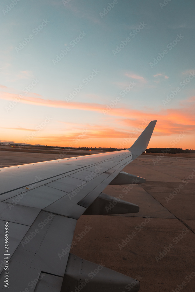 Airplane wing with sunset sky in the background.