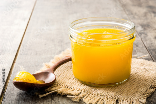Ghee or clarified butter in jar and wooden spoon on wooden table.  photo