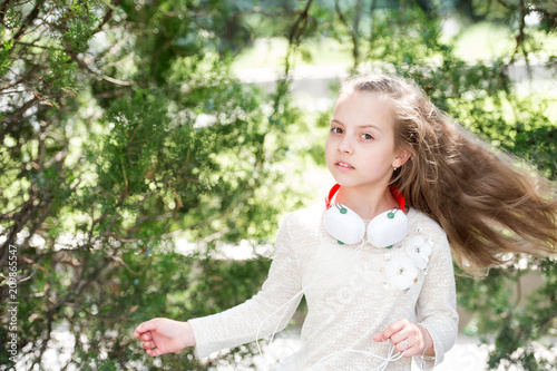 Child dance to music in summer park. Small girl enjoy music in headphones outdoor. Kid dancer with long flying hair. Melody sound and mp3. Summer fun and joy