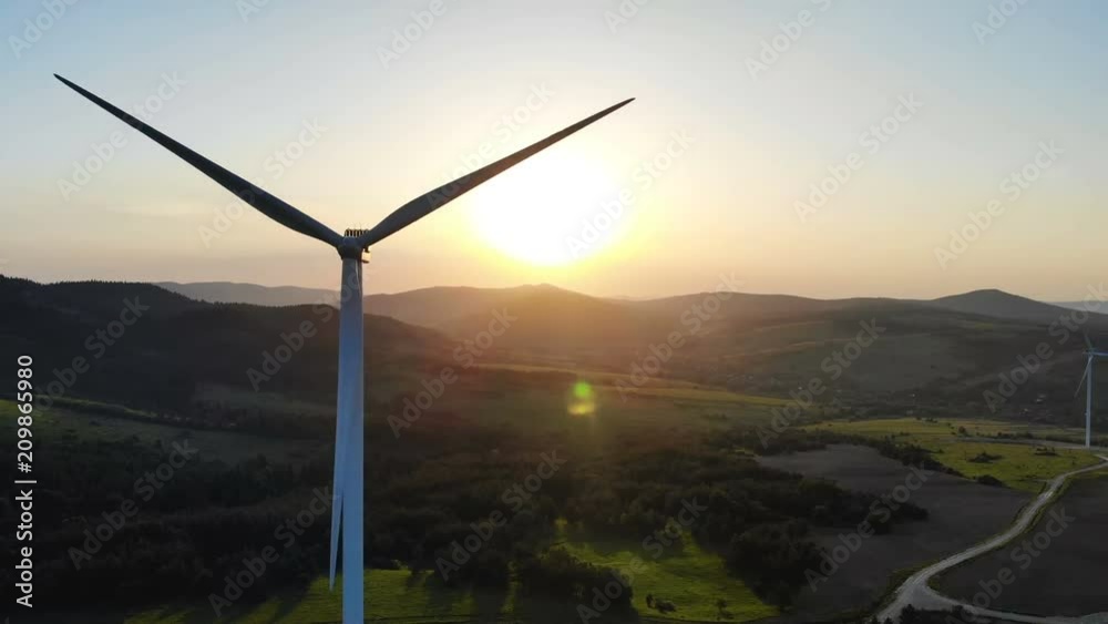 panoramic aerial view of wind turbines with rotating blades on summer fields with beautiful summer fiery sunset on background scenic hillside landscape modern ecosystem renewable energy sources