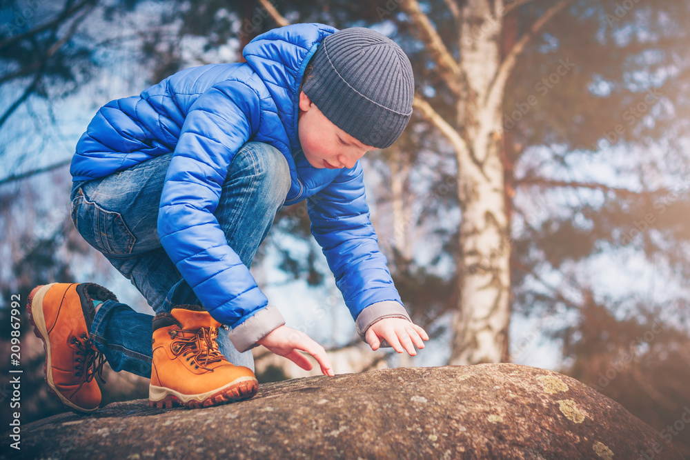 A young ranger in hiking boots climbs the rocks in search of adventure, discoverer and explorer A young ranger in hiking boots climbs the rocks in search of adventure, discoverer and explorer