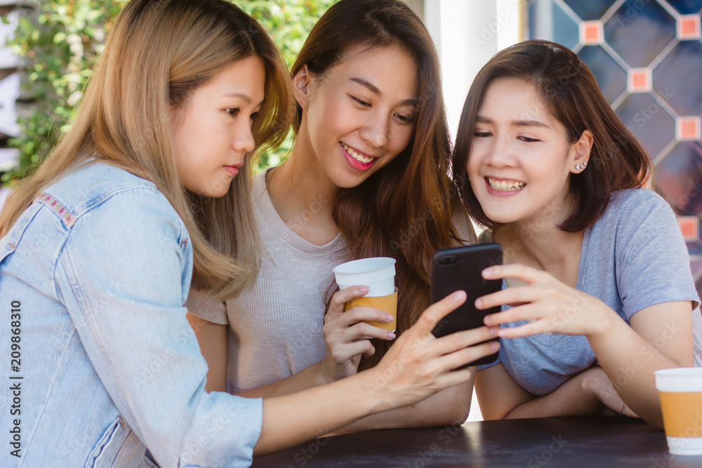 Cheerful asian young women sitting in cafe drinking coffee with friends and talking together. Attractive asian woman enjoying coffee while using smartphone for talking, reading and texting. Cheerful asian young women sitting in cafe drinking coffee with friends and talking together. Attractive asian woman enjoying coffee while using smartphone for talking, reading and texting.