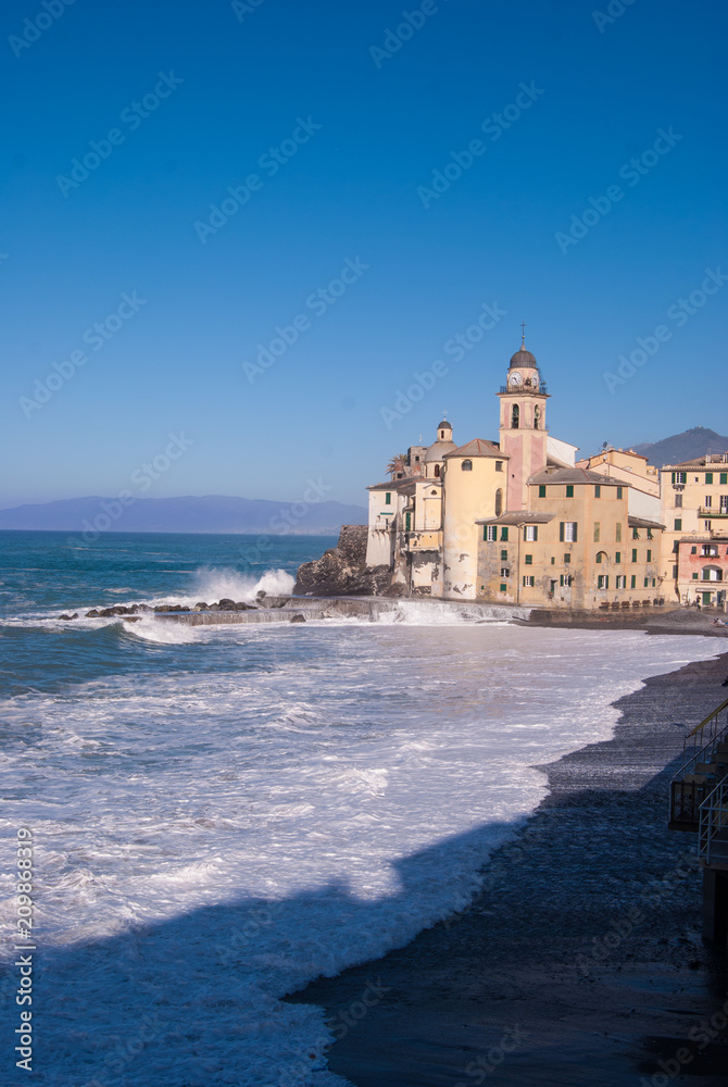 Church of Camogli in a day with sea storm that overwhelms beach and pier - Genoa
