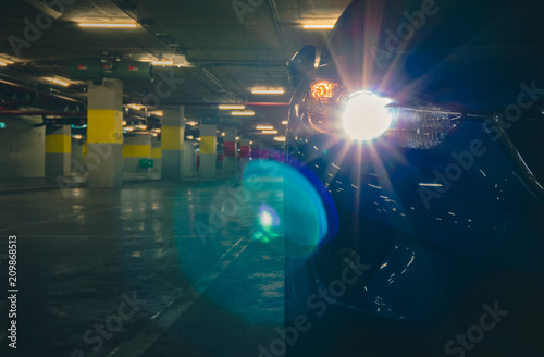 SUV car open headlight light and parked at underground car parking of shopping. Parking lot of shopping mall in the evening. Car parked lonely at night. Car thief at mall concept.