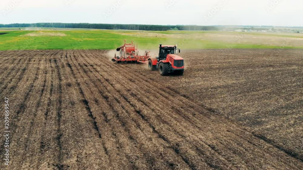 Healthy Food Production Concept. Tractor is sowing a spacious meadow with seeds. Aerial. Healthy Food Production Concept. Tractor is sowing a spacious meadow with seeds. Aerial.