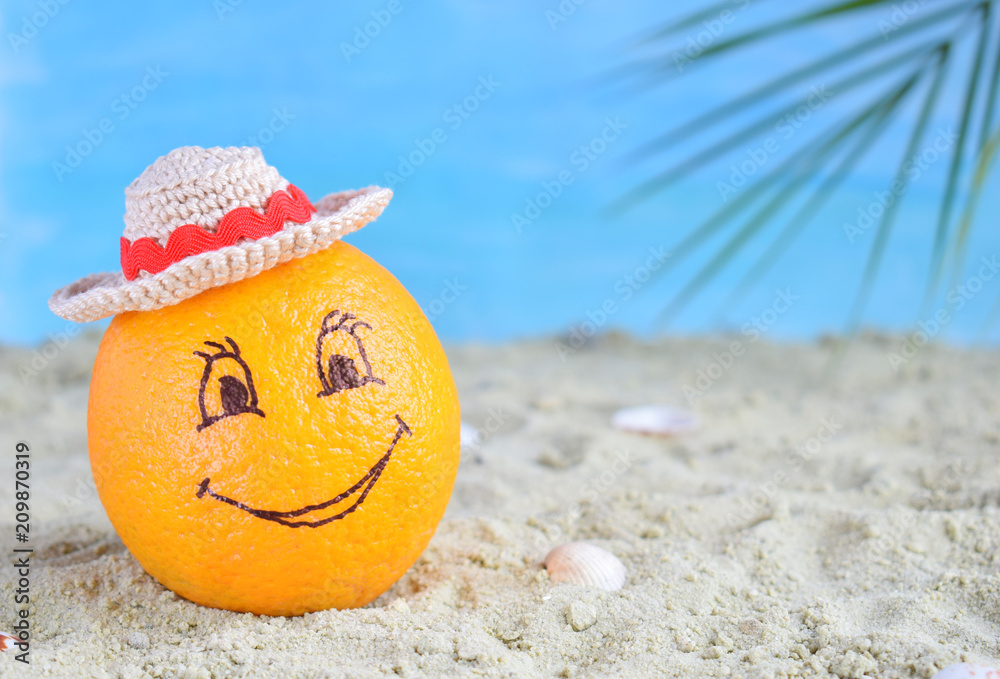 Obraz premium Creative minimal summer idea. Orange citrus hipster in bamboo hat on sand. Tropical beach concept. Creative art. Fun party Mood. Copy space
