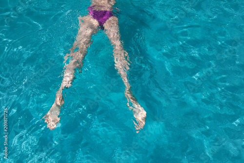 Young girl swimming underwater in the pool
