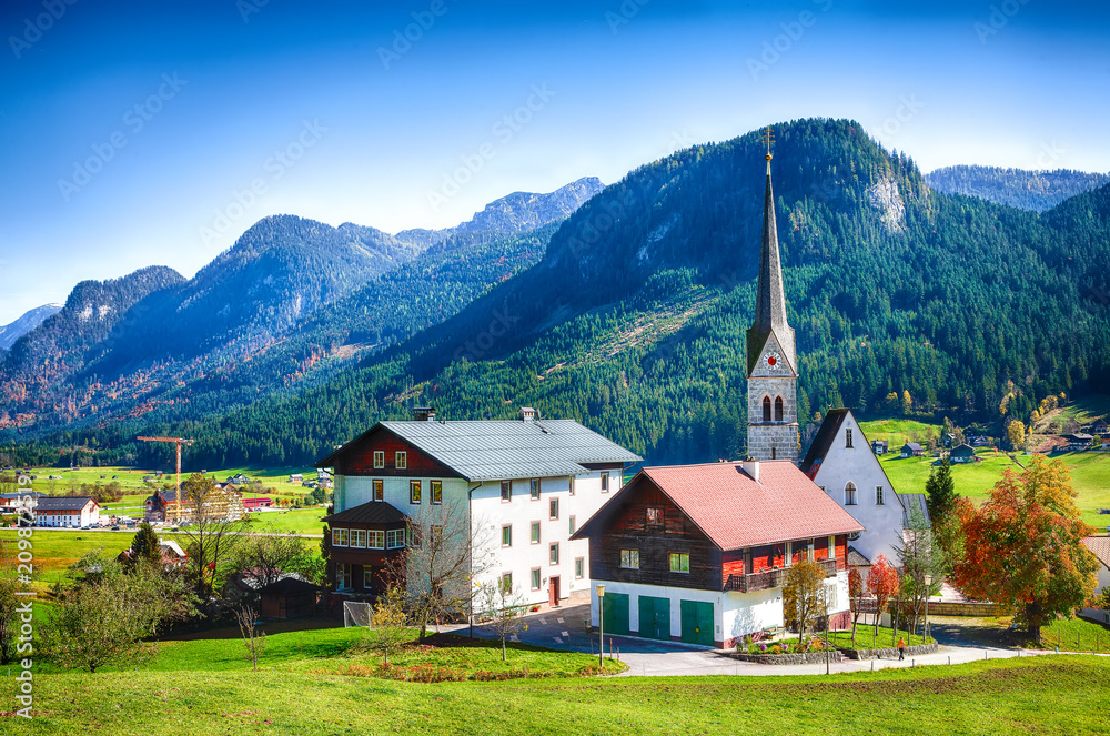 Alpine green fields and traditional wooden houses view of the Gosau village at autumn sunny day.