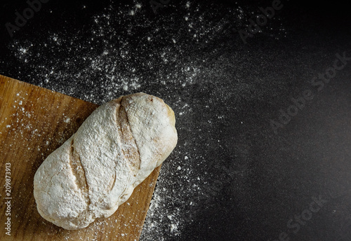 bread on a black background flour on the table