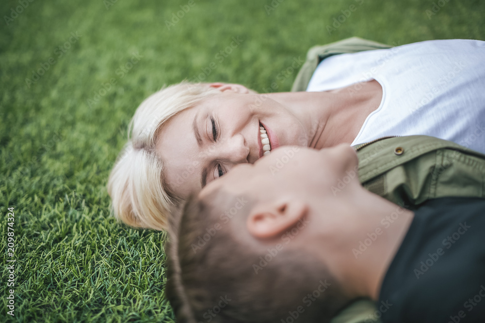 close-up view of happy mother and son lying together on grass, selective focus close-up view of happy mother and son lying together on grass, selective focus