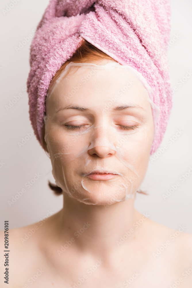 Woman with cosmetic tissue mask on face on light background Woman with cosmetic tissue mask on face on light background