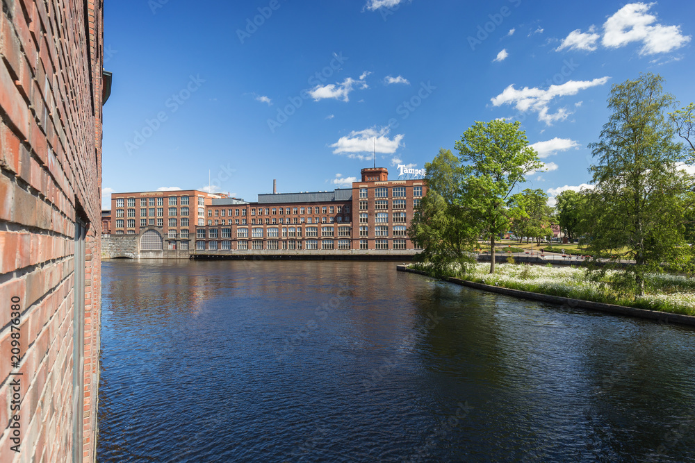 Old red brick industrial buildings along the Tammerkoski rapids in downtown Tampere, Finland on a sunny day. Tampella was an industrial company operating there but now it's a district of the same name