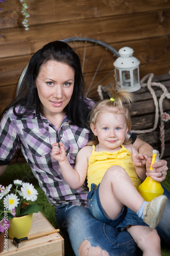 woman is teaching her daughter to plant flowers