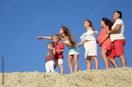 family with children standing together on a sandy hill