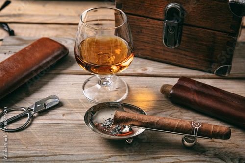 Obraz na plátně Cuban cigar and a glass of cognac brandy on wooden background
