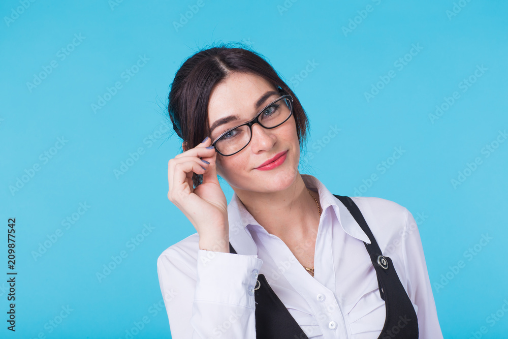A pretty teenage brunette girl with glasses on blue background A pretty teenage brunette girl with glasses on blue background