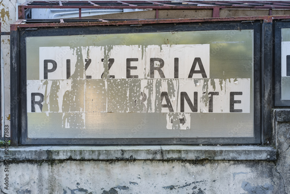 Obraz premium Rundown and weathered Italian pizzeria and restaurant sign on an old wall