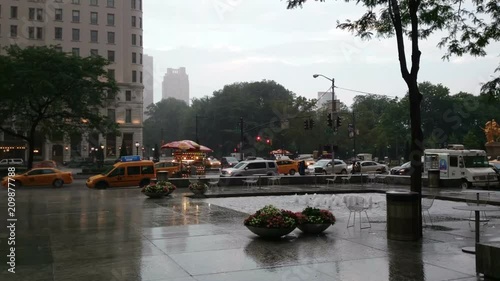 New York City, New York, USA - July 2nd, 2016: Heavy rain in New York City streets across the Central Park, Yellow Cabs and people rushing along the avenue