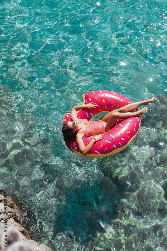 A Woman Floating on Doughnut Ring on Turquoise Sea