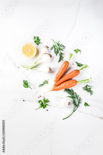 Cooking background with Fresh Vegetables for healthy dinner; carrots, herbs, olive oil, garlic; white marble background flat lay