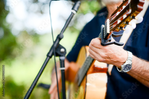 closeup detail of hand playing folk guitar outdoor summer festival
